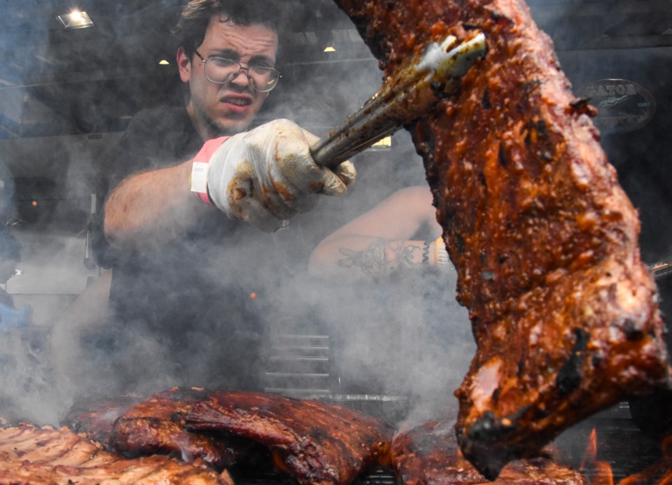 A pittmaster at Gator BBQ checks on a rack of pork ribs