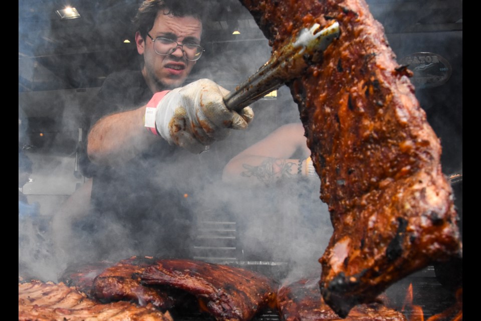 A pittmaster at Gator BBQ checks on a rack of pork ribs