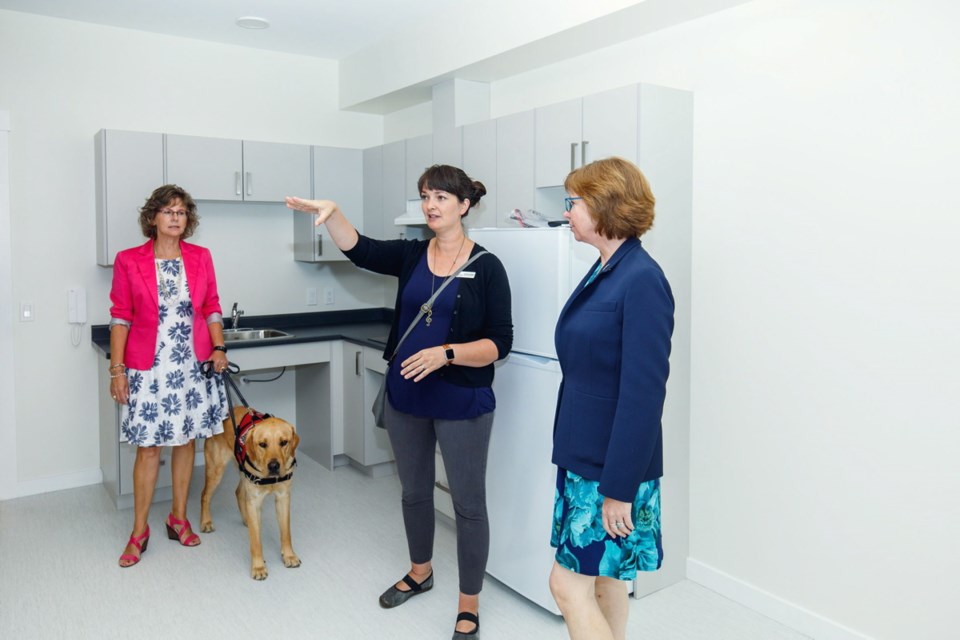 From left: Renate Sutherland of the Oceanside Task Force on Homelessness, with Davie, a guide dog in training, Corrie Corfield, resource development co-ordinator of the Island Crisis Care Society and Sheila Malcolmson, MLA for Nanaimo,check out one of the units.