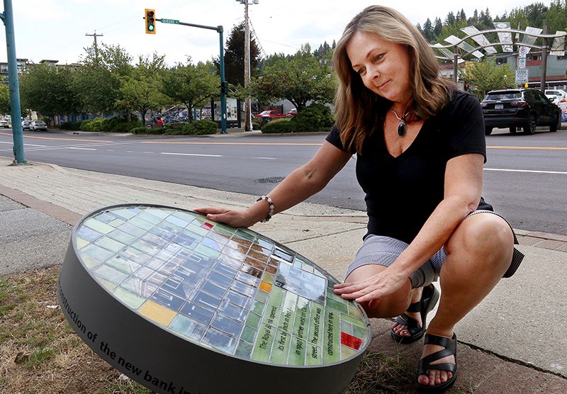 Port Moody councillor Diana Dilworth, who's also chair of the city's heritage commission, checks out one of the tiled mosaics that hilights some of the history and stories about the city's downtown. She said in light of the fire July 28 that destroyed the old Roe & Abernathy grocery store on Clarke Street, that was on the city's heritage register, efforts to highlight that history need to be stepped up.