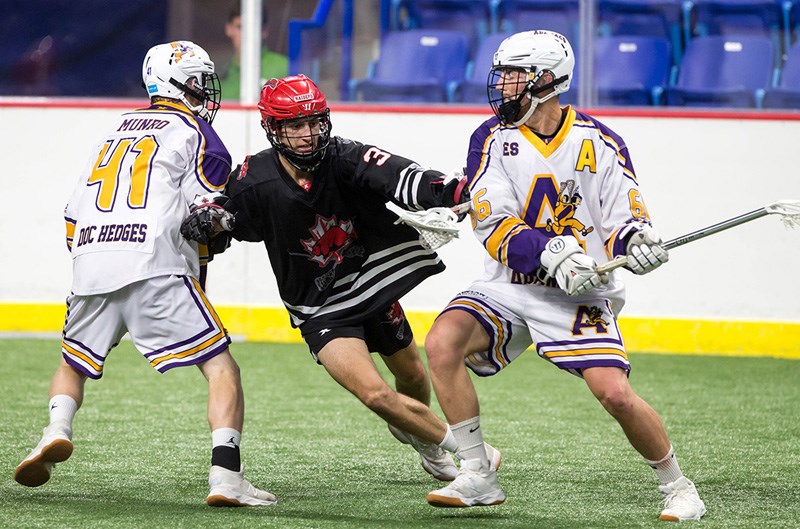 Coquitlam Adanacs forward Dennon Armstrong winds up for a shot as he's checked by an Okotoks Raiders defender in their opening game at the Minto Cup national junior lacrosse championships, Friday at the Langley Events Centre.