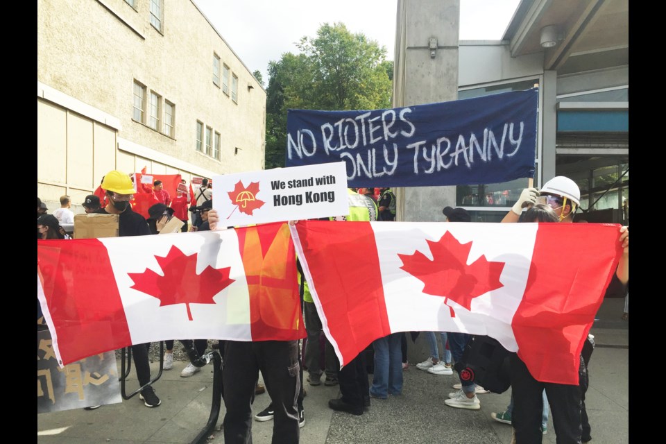 The Pro-Hong Kong side holds Canadian flags in Vancouver on Saturday.