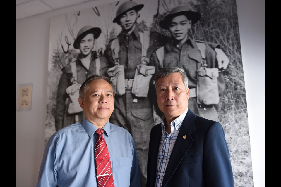 Glen Wong and King Wan, the president of the Chinese Canadian Military Museum Society. In the background is a photo with Glen’s father Bing Chew Wong on the far left.