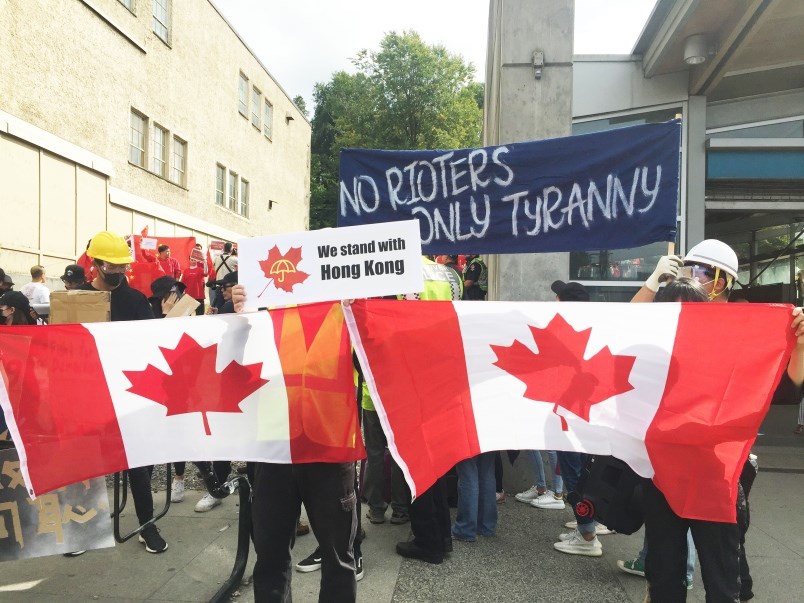 The Pro-Hong Kong side holds Canadian flags at a rally in Vancouver Aug. 17. Photo By Nono Shen