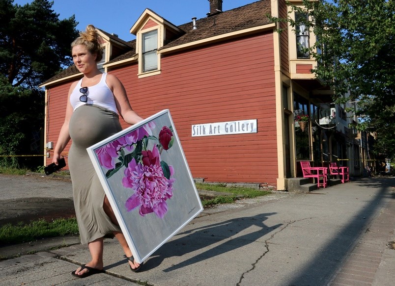 Carola Alder, of CityState Consulting, which shares space in the Silk Art Gallery, carries a paintin