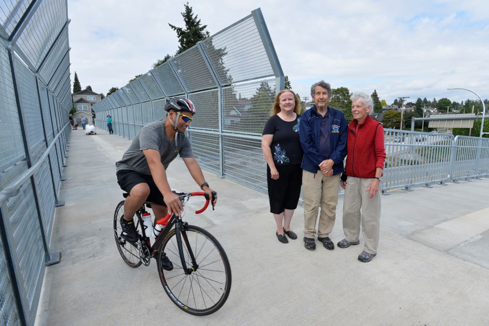 Residents Alice Millar, Gavin McLeod and Mary Wilson admire the new pedestrian/cyclist overpass, while Sheldon Mercade of HUB Cycling passes by.