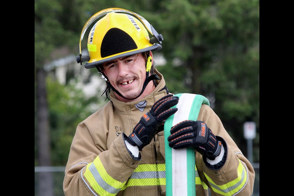 MARIO BARTEL/THE TRI-CITY NEWS
Canadian national rugby player Kyle Baillie rolls up hose after a hands-on tour of Port Coquitlam firehall #1 on Wednesday.