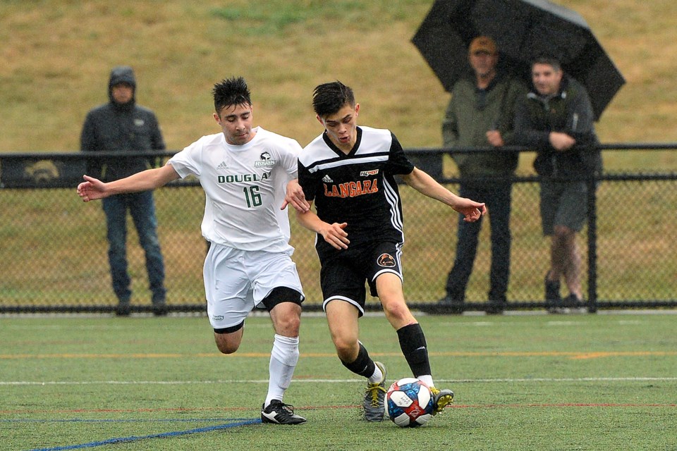Burnaby's Marco Consiglio, at left, sticks close to a Langara Falcons ball carrier during Sunday's PacWest game at Cunnings Turf in Coquitlam. Consiglio's New West-based Douglas College Royals rolled to a 2-0 win, a day after launching the 2019 season with a 2-2 draw.