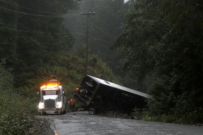 A tow-truck crew removes a bus from an embankment next to a logging road near Bamfield, on Saturday, Sept. 14, 2019. THE CANADIAN PRESS/Chad Hipolito