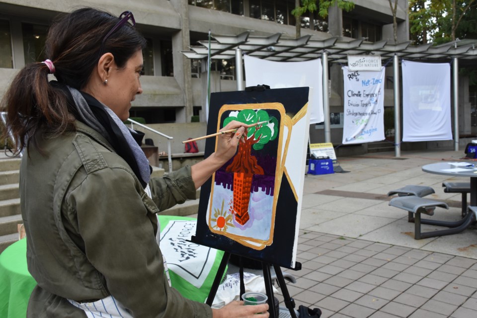 Anne Saint Louis paints a tree opposite a crumbling skyscraper at an art jam outside Burnaby City Hall organized by environmental group Force of Nature.