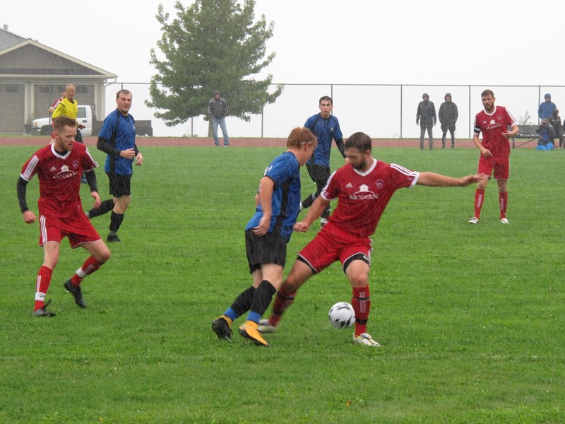 SOCCER BEGINS: Powell River Villa player Daniel Paul [centre, in red] works to keep the ball away from Juan de Fuca All Flows players [in blue] during a rainy season opener at Timberlane Park on Saturday, September 14. Vanessa Bjerreskov photo