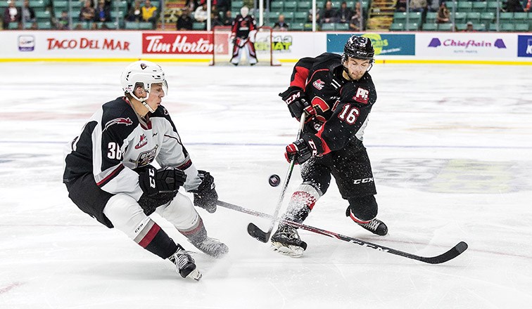 Prince George Cougars defender Ryan Schoettler tries to put a shot on goal past Vancouver Giants defender Justin Lies on Friday night at CN Centre during the Cougars home opener. Citizen Photo by James Doyle