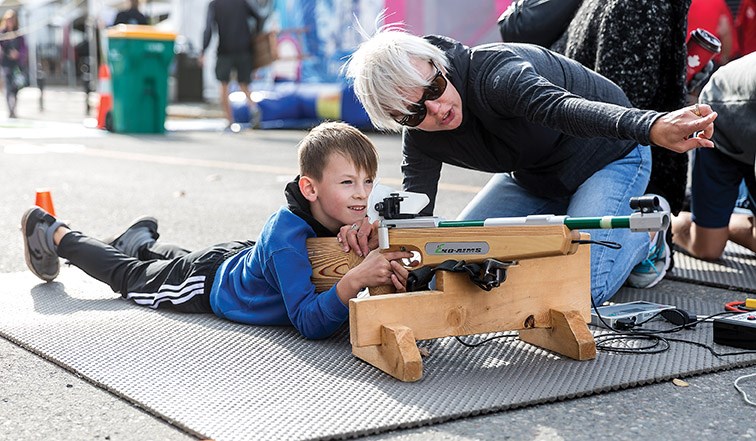 Stacey Sinclair, a volunteer parent with the Caledonia Nordic Ski Club, shows Davyn Hogan, 7, how to aim the biathlon laser rifle at the CrossRoads Powersports, Skiing and Snowboarding Festival on Saturday morning. Citizen Photo by James Doyle