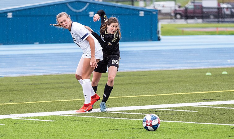 UNBC Timberwolves forward Sofia Jones eyes up the loose ball while dodging a Mount Royal University Cougars defender on Sunday afternoon at Masich Place Stadium. Citizen Photo by James Doyle