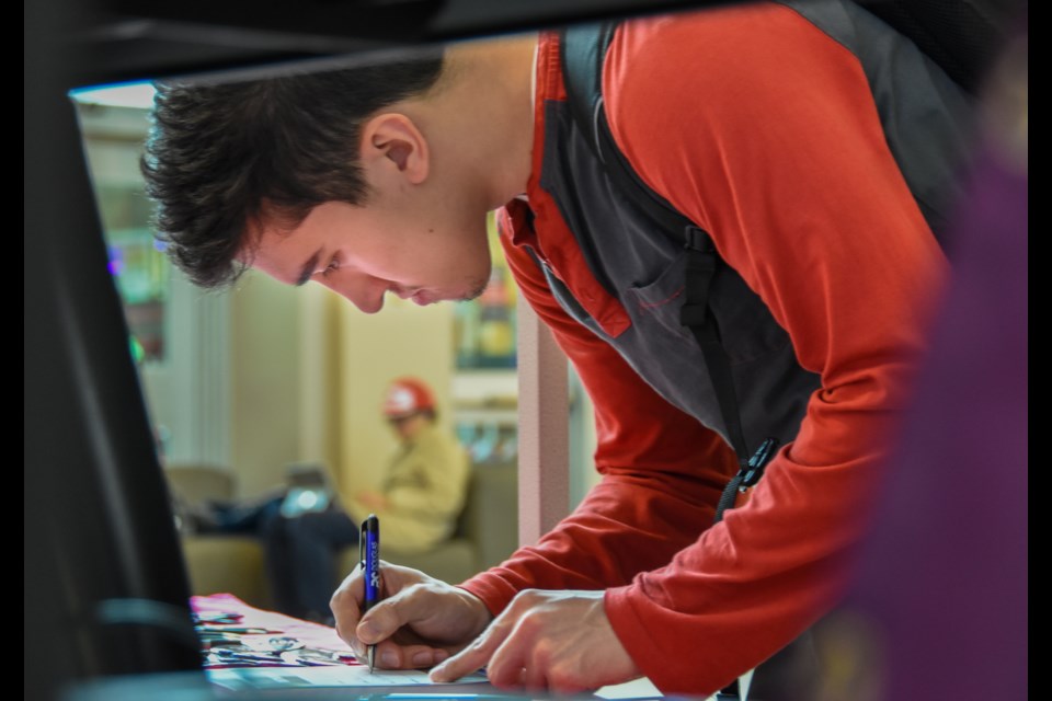 Douglas College student Jonah Roesler, 22, signs a pledge to vote in the upcoming federal election