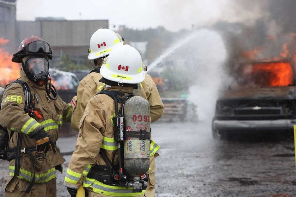 Burnaby fire Captain Kris Anderson leads Burnaby NOW reporter Cornelia Naylor and Burnaby city Coun. Joe Keithley in a firefighting exercise at Fire Ops 101 in Vancouver Monday.