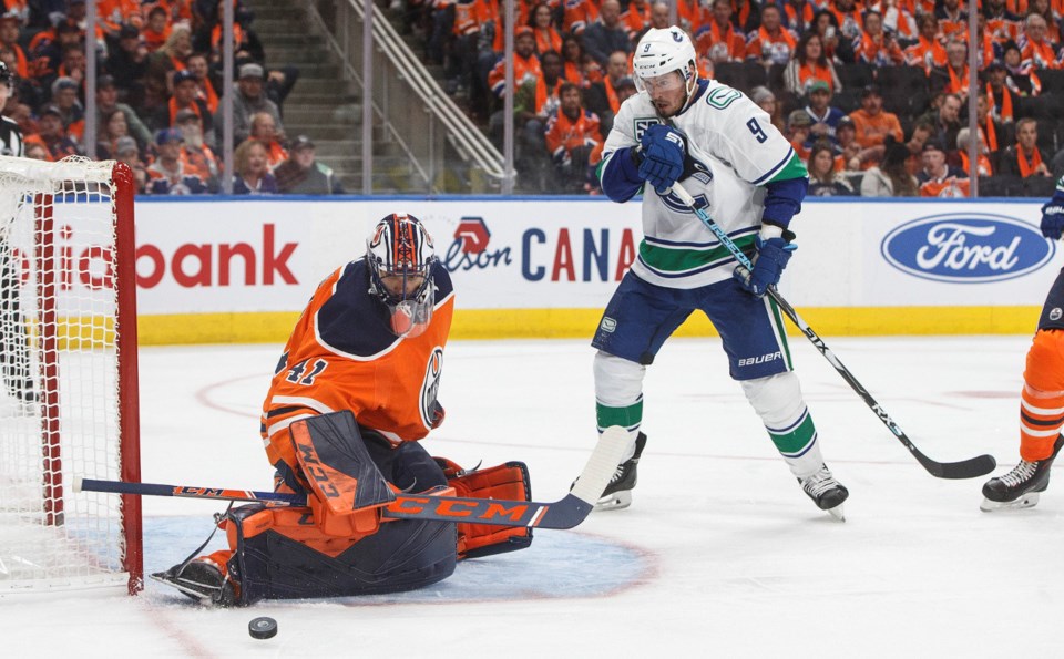 The Vancouver Canucks' J.T. Miller looks on as Mike Smith of the Edmonton Oilers makes a save