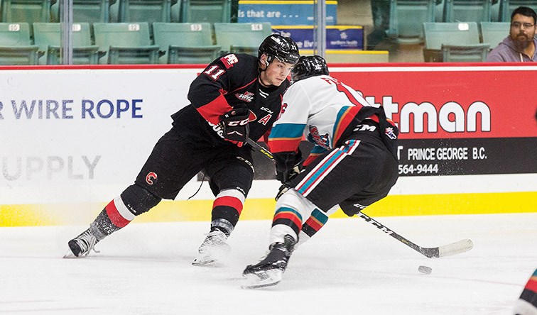 Prince George Cougars forward Josh Maser looks to make a play while being checked by Kelowna Rockets defender Michael Farren on Friday evening at CN Centre. Citizen Photo by James Doyle