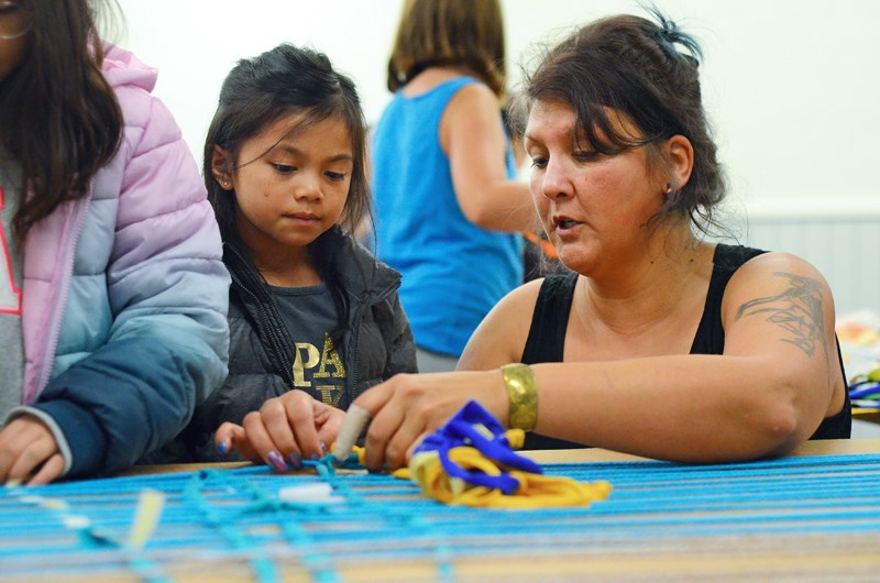 Semiahmoo artist and cultural historian Roxanne Charles helps Cascade Heights Elementary student Phoebe Doctor weave with recycled materials at the inaugural Indigenous Week of Learning at Burnaby Village Museum Tuesday.