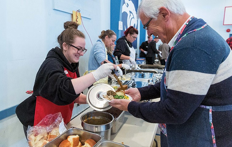 Volunteers load up plates of food for guests at Sacred Heart auditorium on Sunday during St. Vincent de Paul Society’s annual Thanksgiving Dinner. Citizen Photo by James Doyle