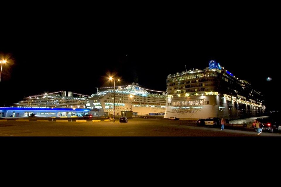 Three cruise ships glow in the night under their own power at Ogden Point.