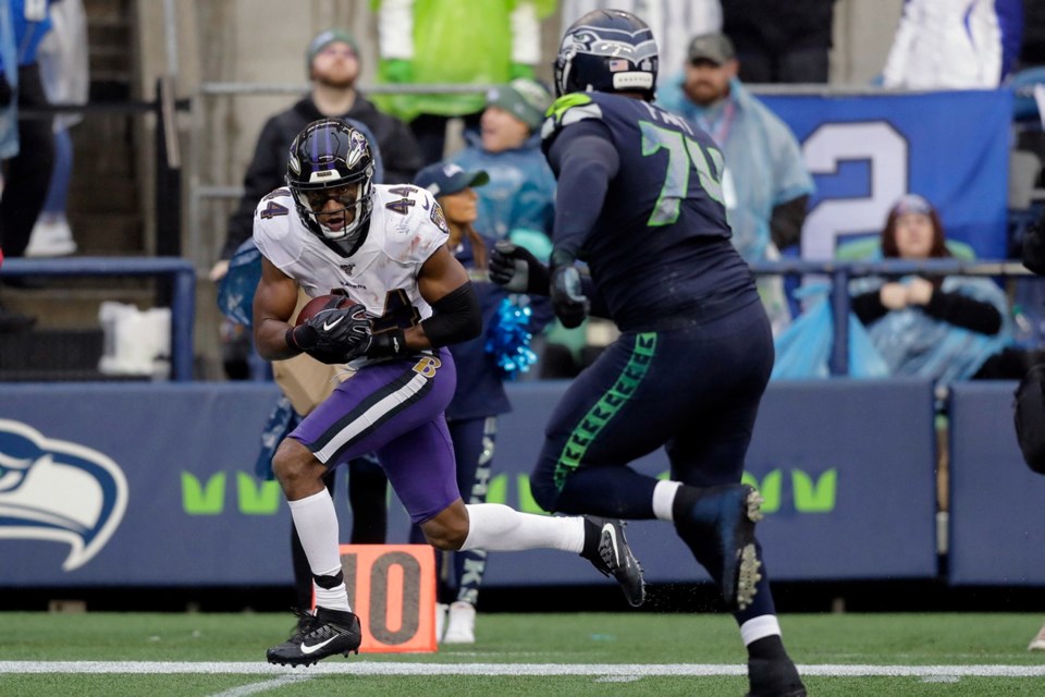Baltimore Ravens cornerback Marlon Humphrey (44) runs for a touchdown after recovering a Seattle Seahawks fumble as Seahawks offensive tackle George Fant, right, pursues, during the second half of Sunday's game in Seattle.