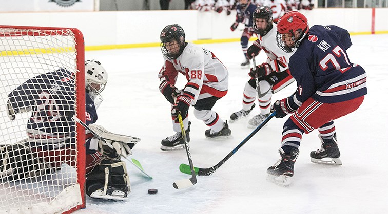 Cariboo Minor Midget Cougars player Decker Mujcin tries to tuck the puck under sliding Greater Vancouver Minor Midget Canadians goaltender Dylan Lowe while being checked by Canadians defender Timothy Kim on Sunday morning at Kin 2. Citizen Photo by James Doyle