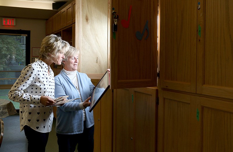 Diane Johnston, president of Club Bel Age's board of directors, and Lisa Kamerling, the club's coordinator, look through old photos as the Maillardville seniors organization prepares to shut down at the end of the year.