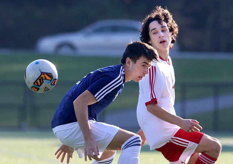 MARIO BARTEL/THE TRI-CITY NEWS
Dr. Charles Best Blue Devil Dominic Tomasetti keeps his eye on the ball as he battles a Terry Fox Ravens defender Andrew Cerqueira in the first half of their Fraser North Athletic Association senior boys soccer district semifinal, Thursday at Dr. Charles Best secondary. The Devils battled back from a 2-0 deficit early in the second half to win, 4-2. Tomasetti scored the winning goal after Lieto Hutchinson and Hamish Ogden got them back on even terms. Erwin Perez scored the insurance goal. The win assured Dr. Charles Best a spot in the provincial championship later this month. They'll play Moscrop secondary, from Burnaby, in next Thursday's district final.