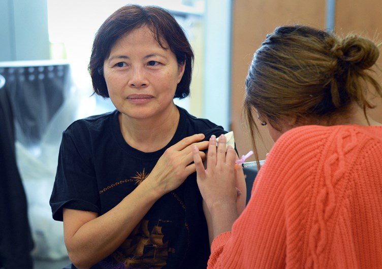 Burnaby resident Regina Leung braces for a shot during a flu clinic at Edmonds Community Centre Monday.