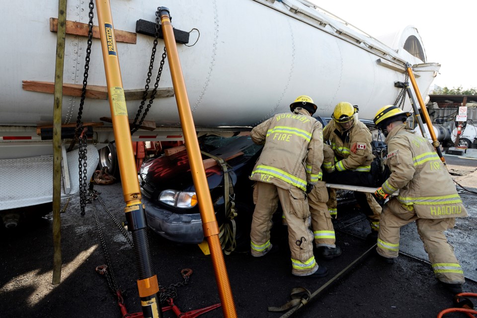 Burnaby firefighters extract a mannequin from a passenger vehicle pinned under a rolled tanker truck in a training simulation at ABC Recycling in Burnaby Sunday.