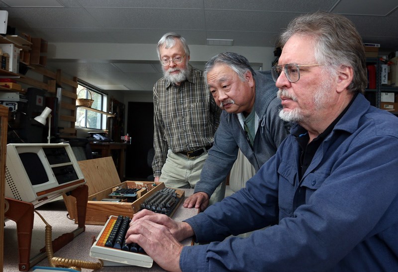 David Querbach sits at his old Orotona Attaché portable computer in the workshop of his Port Moody home, while former colleagues from the West Coast Computer Society, Al Mar and Dave Wiens, wonder if it will boot up. Members of the society, the first of its kind that formed in the Lower Mainland, in 1976, are holding a reunion in Coquitlam on Saturday.