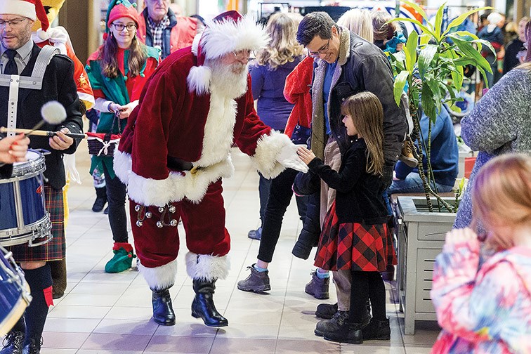 Santa gives a young girl a high-five during his arrival at Pine Centre Mall on Saturday morning. Citizen Photo by James Doyle