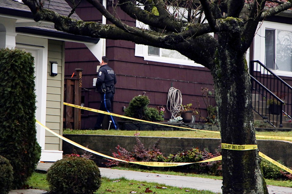 A New Westminster Police Department officer enters the backyard of a house where a shooting took place Sunday evening.