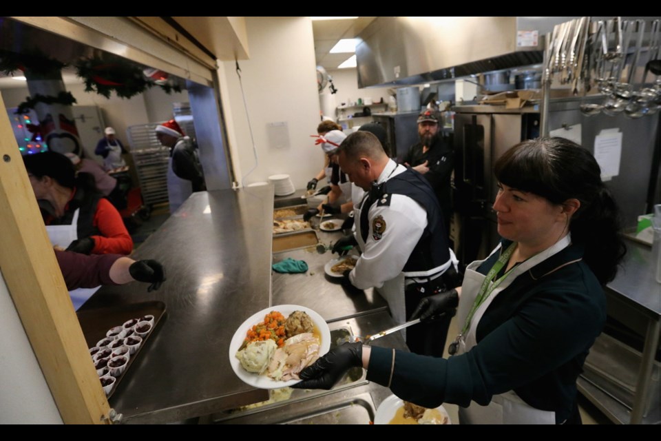 Volunteers serve up food during the 2018 Christmas Community Meal at Our Place. This year's community meal is being held on Tuesday.