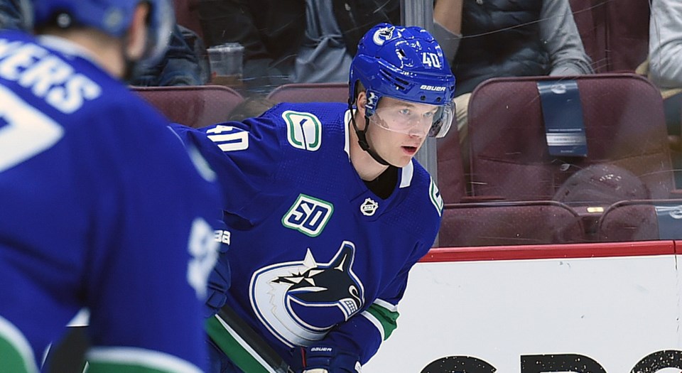 Elias Pettersson passes the puck to Tyler Myers for the Vancouver Canucks.