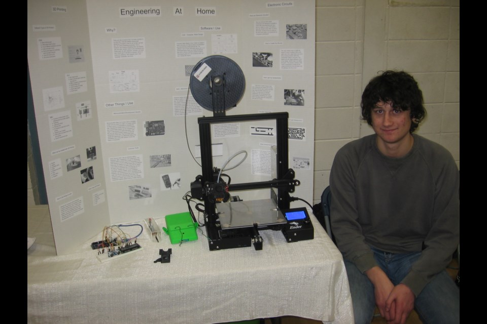 Noah Klager sits next to the 3-D printer he's programmed to create a whistle for his display during the Capstone Celebration Tuesday afternoon at Prince George Secondary School.