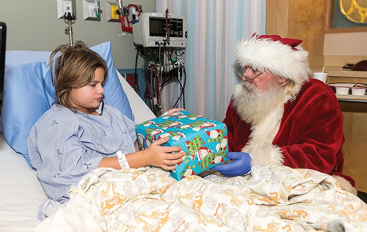 Citizen Photo by James Doyle. Nine-year-old Katrina Voss gets a gift from Santa Claus on Wednesday morning during Santa’s surprise visit to the Pediatric Unit of University Hospital of Northern B.C.