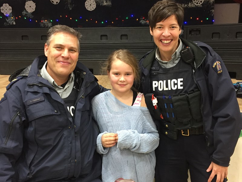 Powell River RCMP corporal Aaron Hamilton [left] and constable Paula Perry [right] helped serve students, including grade-three student Hollie-Mae Jacques [centre], at the annual Henderson Elementary School pancake breakfast. Contributed photos