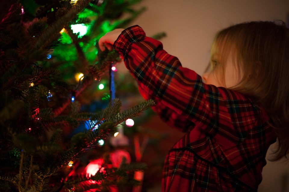 Stock photo of girl putting an ornament on the tree.