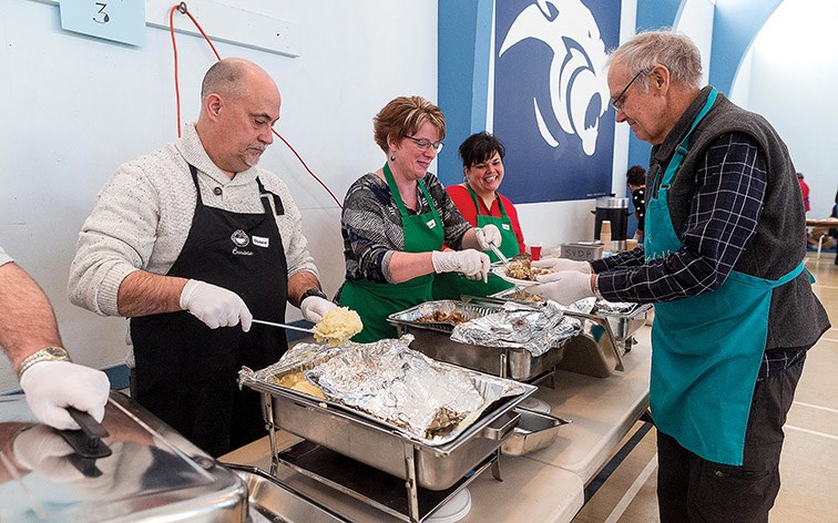 Citizen Photo by James Doyle. Stuffing and potatoes are scooped onto a plate of turkey dinner with all the trimmings at Sacred Heart auditorium on Wednesday during the 47th Annual St. Vincent de Paul Christmas Day Dinner.