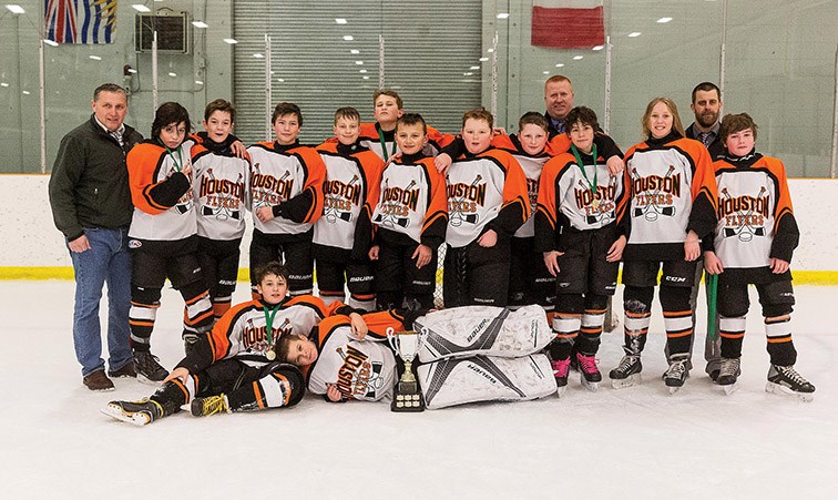 Citizen Photo by James Doyle. Players and coaches from the Houston/Burns Lake Flyers pose for a photo with their trophy on Sunday afternoon at Kin 2 after winning the House Level 1 championship of the 10th Annual Ethan Blacker Memorial Peewee Tournament.