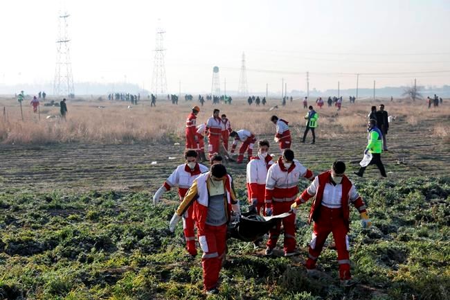 Rescue workers recover the bodies of victims of a Ukrainian plane crash in Shahedshahr, southwest of the capital Tehran, Iran, Wednesday, Jan. 8, 2020. A Ukrainian airplane carrying over 170 people crashed on Wednesday shortly after takeoff from Tehran's main airport, killing all onboard. (AP Photo/Ebrahim Noroozi)