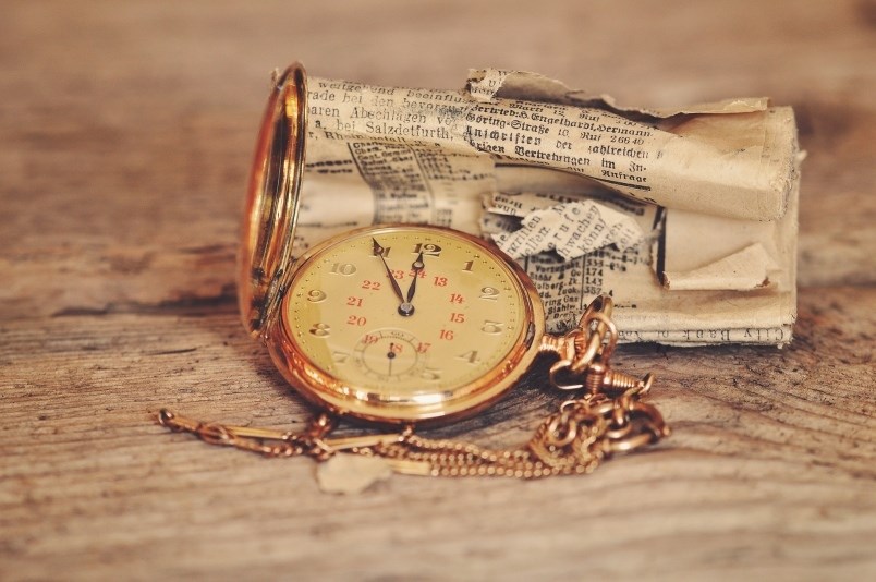 A pocket watch and rolled up, tattered newspaper.