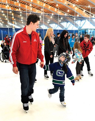 Vancouver Canucks forward Mason Raymond skates along side a young girl at the Scotiabank Group Charity Challenge at the oval on Monday.