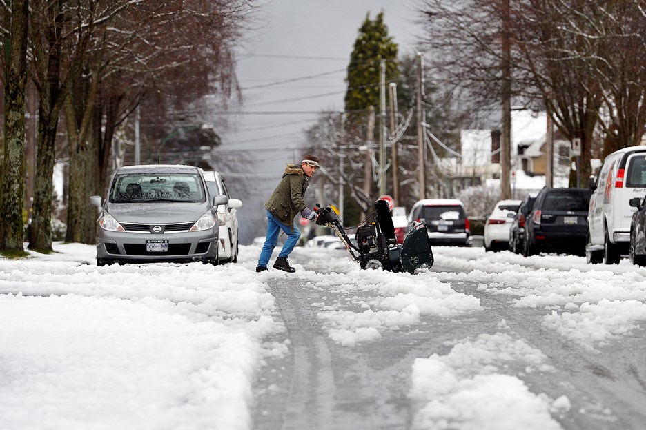 A man pushes a snow blower across an icy Burnaby street. Jennifer Gauthier photo
