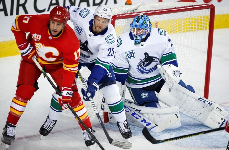 Milan Lucic and Alex Edler battle for position in front of Jacob Markstrom.