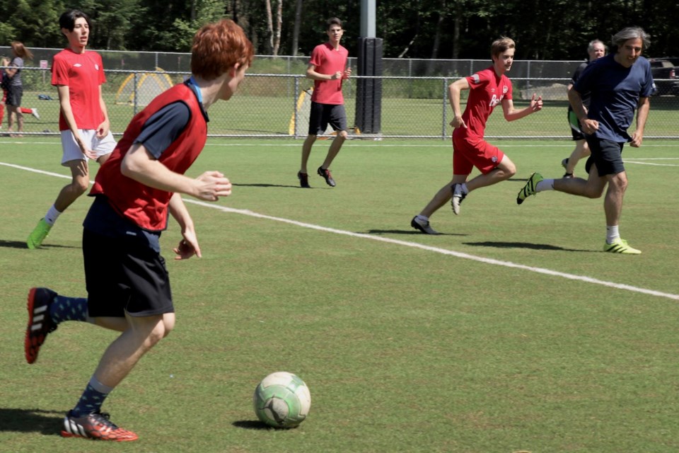 Young men playing soccer on the artificial turf field.