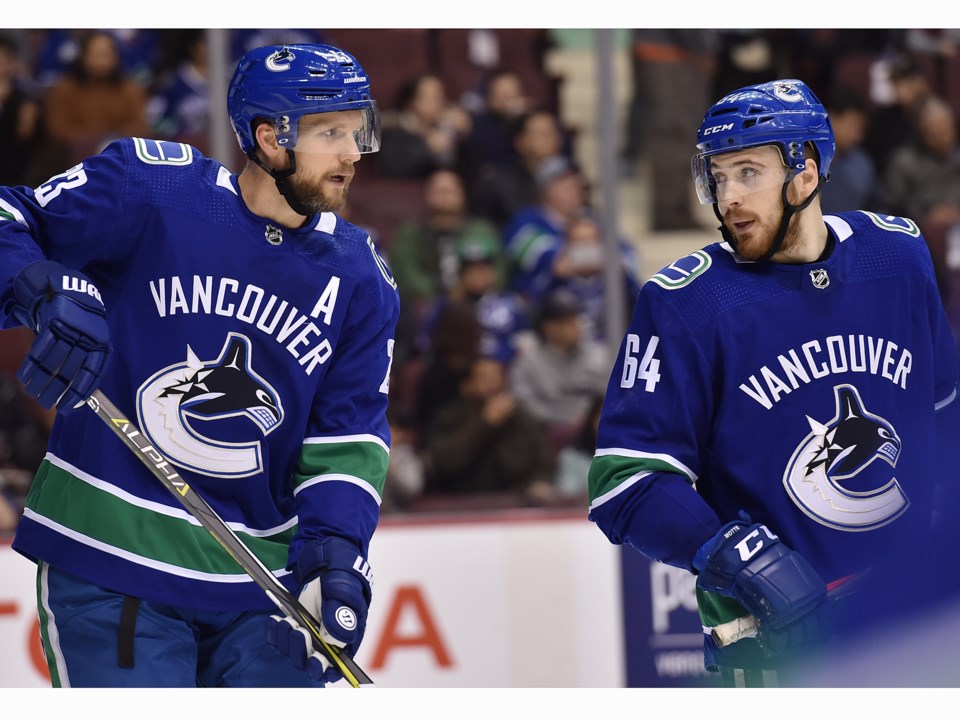 Tyler Motte talks to Alex Edler before a faceoff.