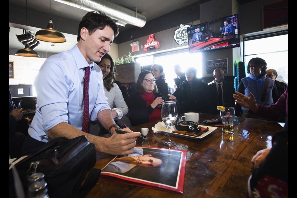 Prime Minister Justin Trudeau signs a picture of himself while greeting people at C.J. Barley's Pub and Grill in Keswick, Ont., in January 2019.